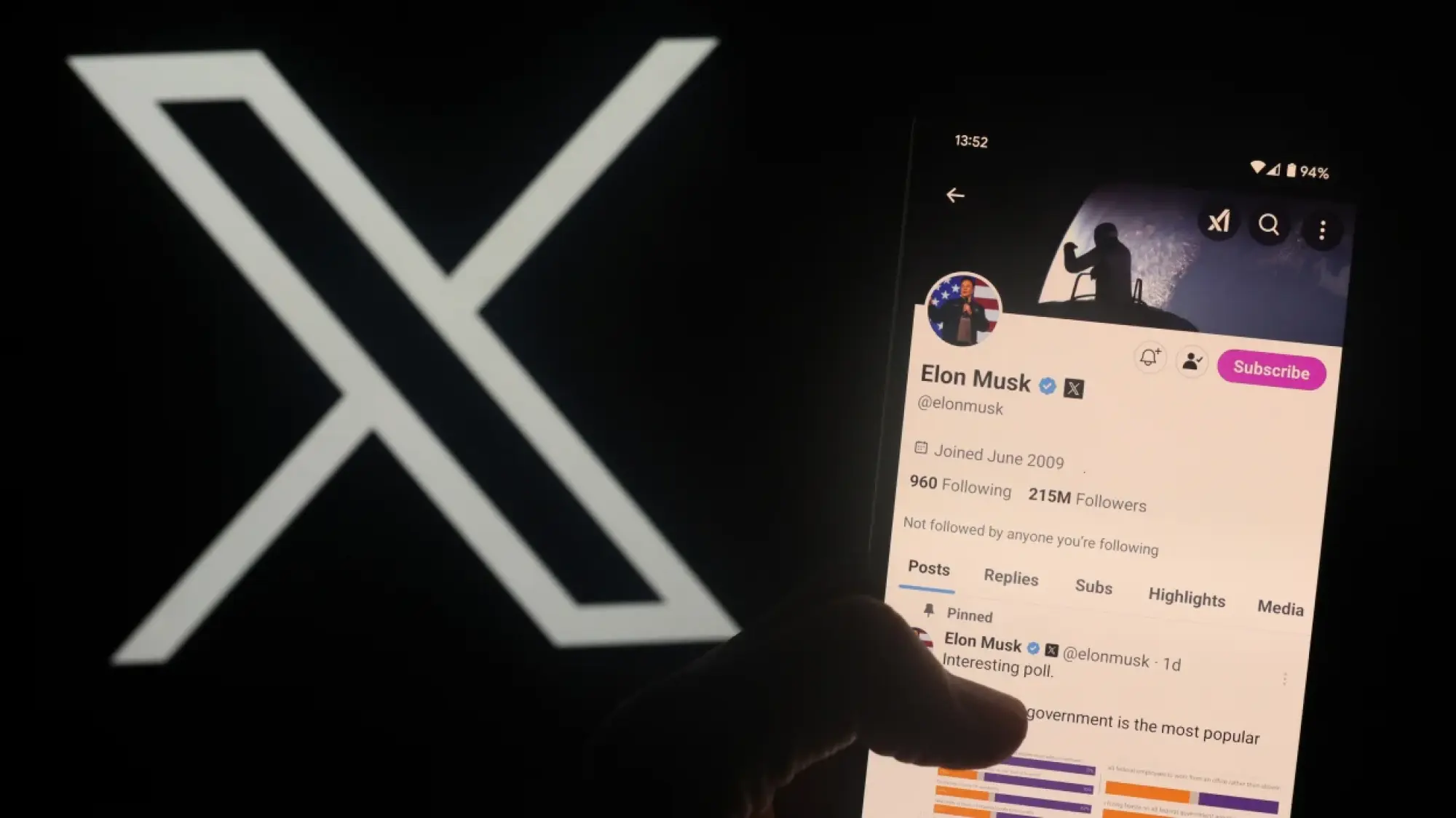 a user holds up phone showing elon musk's x feed in front of x logo